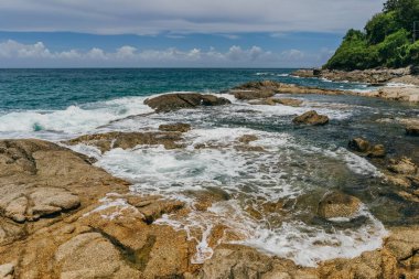 Bulutlu hava ışıklarında okyanus dalgalarıyla kayalık uçurum kıyısı. Yaz tatili ve doğa yolculuğu macera konsepti.