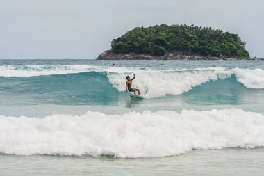 Kata beach, Phuket, Thailand - 16.06.2021: men catching waves in ocean, isolated Surfing action water board sport. people water sport lessons and beach swimming. High quality photo
