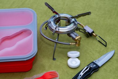 Silikon kırmızı bir kap, plastik bir çatal ve açık hava için bir brülör.