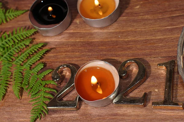 Burning candle figures 2021 and fern on wooden background — Stock Photo, Image