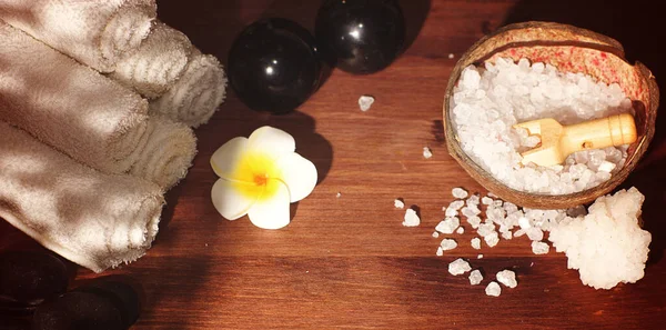 Conjunto para tratamentos de spa e pedras de massagem quente com flor de plumeria branca em fundo de madeira Fotografia De Stock