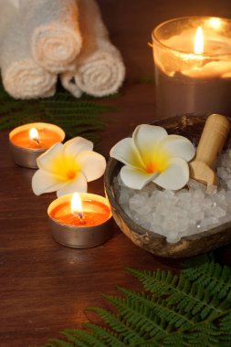 Kürek, yanan mumların arka planında banyo tuzunda yatar..