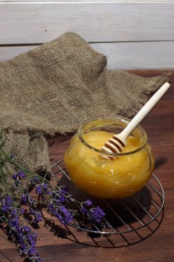 Bir kavanoz sarı bal, lavanta buketinin yanında..