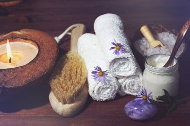 Masanın üzerinde yanan bir mum ve spa tedavisi için bir kavanoz beyaz kozmetik ürünü duruyor..