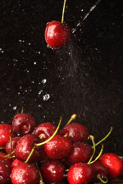 Ein Wasserstrahl Schlägt Eine Rote Kirschbeere Auf Dunklem Hintergrund — Stockfoto