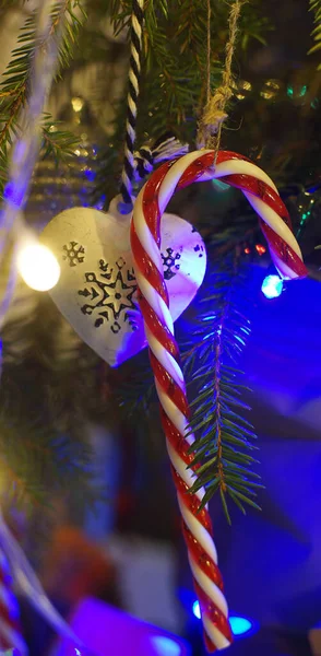 Weihnachtsspielzeug Karamellen Hängen Zweigen Umgeben Von Leuchtenden Girlanden Senkrecht — Stockfoto