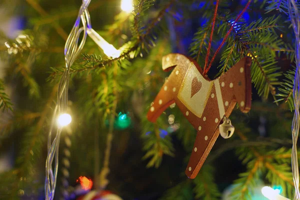 Weihnachten Spielzeugpferd Hängt Zweigen Eines Weihnachtsbaums Mit Hellen Girlanden — Stockfoto