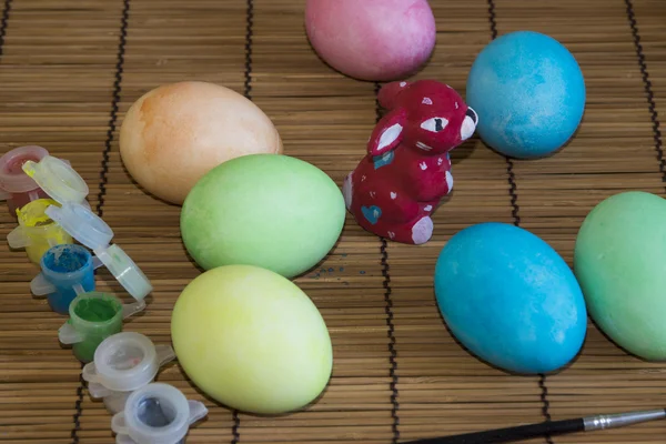 Easter Bunny i kolorowych jaj na stole z farbą — Zdjęcie stockowe