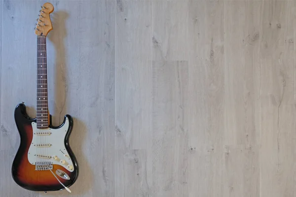 Gri ahşap zeminde güneş patlaması renginde gitar.