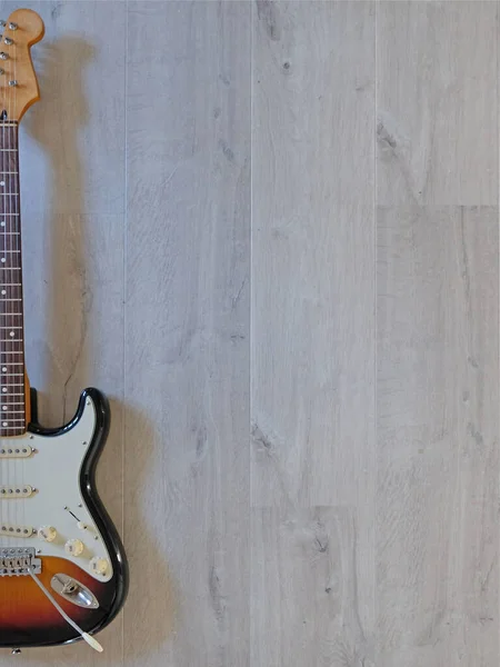 Gri ahşap zeminde güneş patlaması renginde gitar.