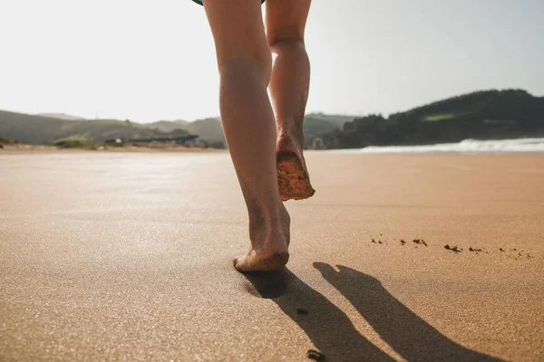 Çocuk sahilde yürüyor ve ayak izleri bırakıyor.