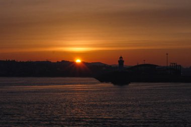 Sahilde gün doğumu Bir deniz feneriyle