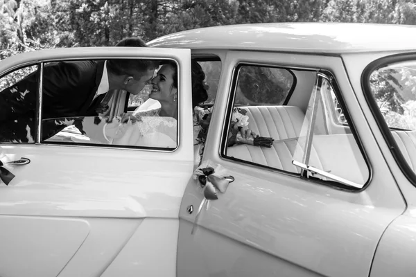Beautiful brunette bride in retro car — Stock Photo, Image