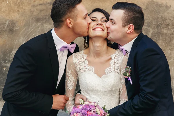 Dois noivos bonitos beijando noiva — Fotografia de Stock