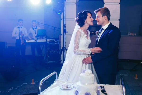 Feliz hermosa recién casados con pastel de boda — Foto de Stock