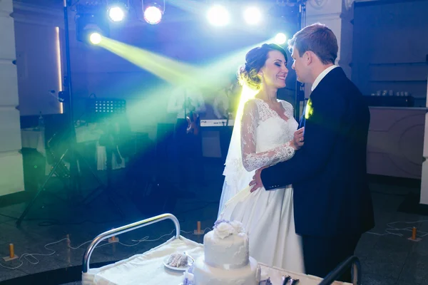 Gelukkig mooi jonggehuwden met bruidstaart — Stockfoto