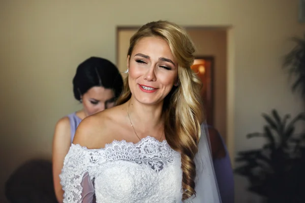 Bridesmaids helping beautiful blonde bride get ready for wedding — Stock Photo, Image