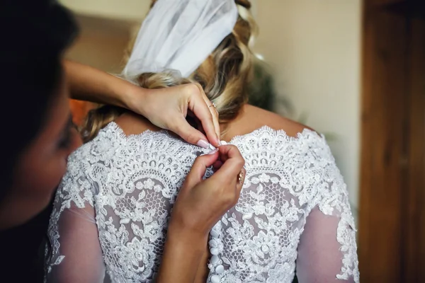 Damas de honor ayudando a hermosa novia rubia prepararse para la boda —  Fotos de Stock