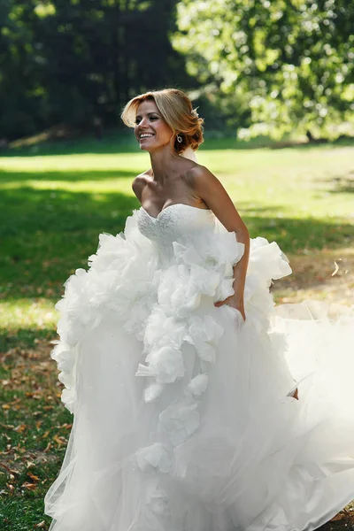 Happy krásná nevěsta tančí v parku — Stock fotografie