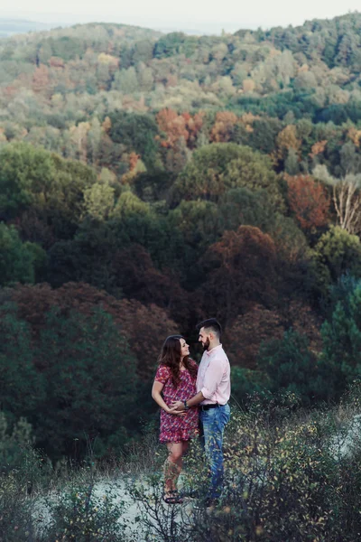 Marido y mujer embarazada abrazándose en el bosque — Foto de Stock