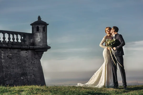 Novomanželé líbání v blízkosti středověkého hradu — Stock fotografie