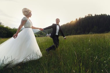 Yeşil çimenlerin üzerinde günbatımında çalışan Düğün çifti