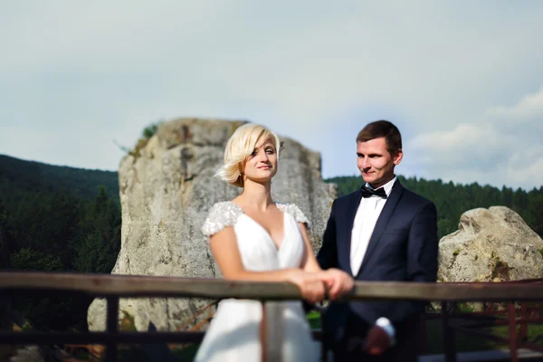 Marié vient à la mariée debout près de la clôture sur la montagne — Photo