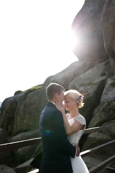 Noiva e noivo posando na montanha em um dia ensolarado — Fotografia de Stock