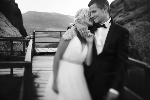 Casamento casal andando na ponte nas montanhas — Fotografia de Stock