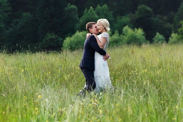 Свадебная пара, бегущая по зеленой траве на закате — стоковое фото