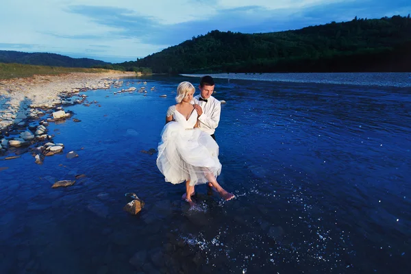 Wedding couple running on green grass at sunset — Stock Photo, Image