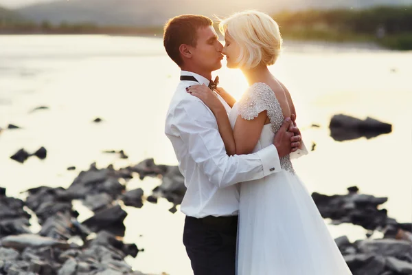 Casamento casal correndo na grama verde ao pôr do sol — Fotografia de Stock