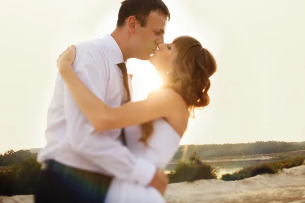 Portrait of bride and groom kissing on the background of rays of — Stock Photo, Image