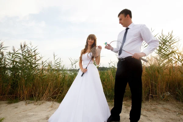 Glücklicher Bräutigam und Braut spielen Tennis an seinem Hochzeitstag — Stockfoto