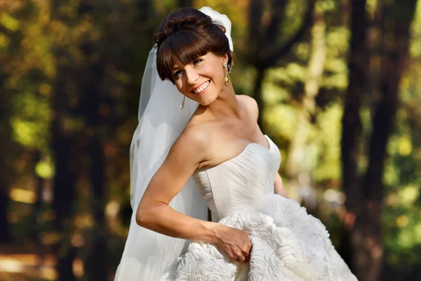 Noiva segurando um vestido e sorrindo — Fotografia de Stock