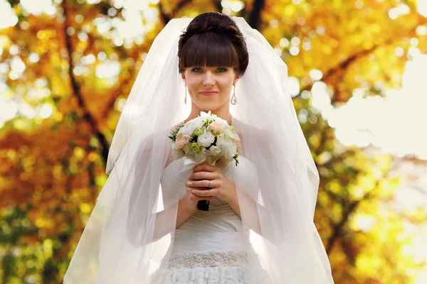 Sposa con un bouquet in piedi al sole nel parco — Foto Stock