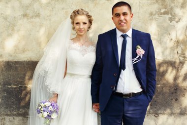 Gelin ve damat duvar arka plan üzerinde duran