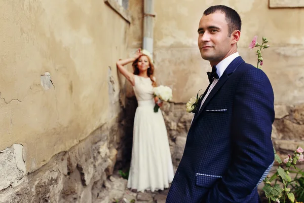 Bruid in krans van witte roos en bruidegom op de achtergrond — Stockfoto