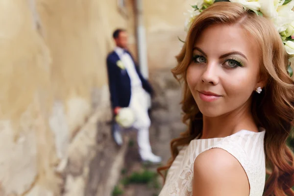Bride in wreath of white rose and groom on the background — Stock Photo, Image