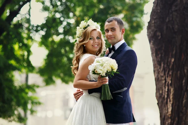 Bruden och brudgummen med en bukett står i parken — Stockfoto