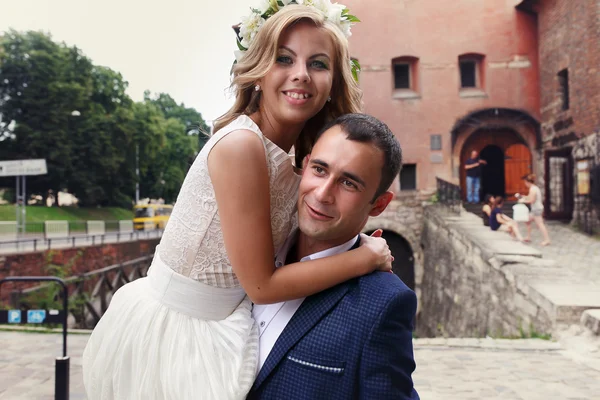 Handsome bridegroom carrying his beautiful laughing bride in his — Stock Photo, Image