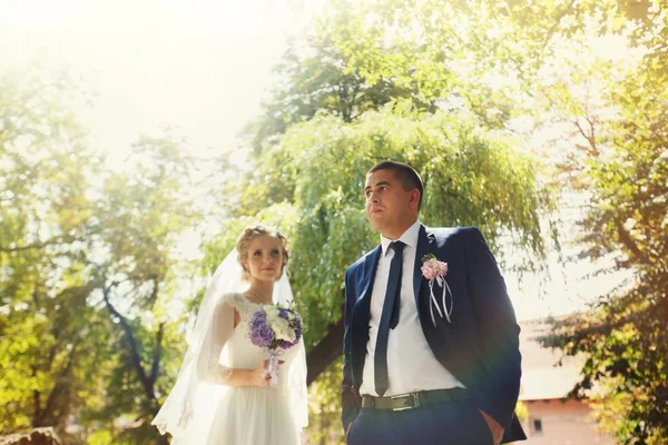 Bruden och brudgummen med en bukett står i parken — Stockfoto