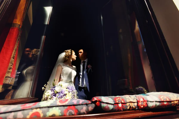 Lyckliga bruden och brudgummen i windows av tegel vägg i bröllop promenad — Stockfoto