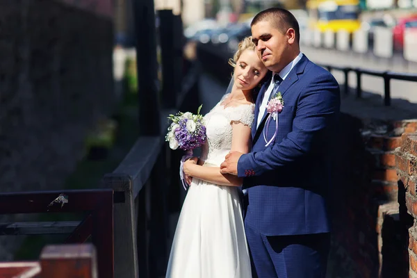 A noiva e o noivo com um buquê em pé ao sol e perto — Fotografia de Stock