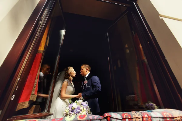 Happy bride and groom in windows of brick wall in wedding walk — Stock Photo, Image