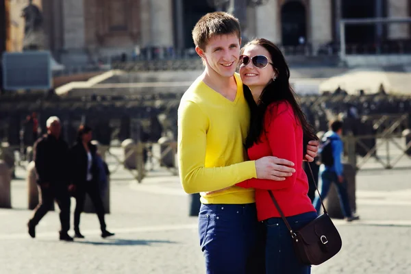 A couple of tourists smiling and enbracing on the central square — Stock Photo, Image