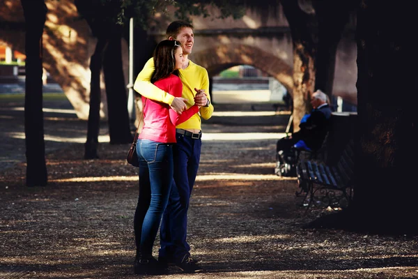 Nuori pari kävelee puistossa puiden keskellä — kuvapankkivalokuva