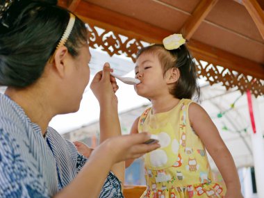 Küçük bir kız, 3 yaşında, okula gitmeden önce sabah erkenden annesi tarafından kahvaltı ettiriliyor.