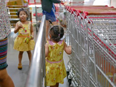 Bir kız bebek etrafta dolanıyor ve annesi alışveriş yaparken öylece oturamıyor.