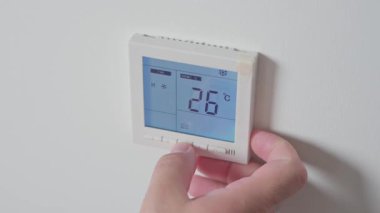 Adam klimayı açıyor ve yakın plan çekimde beyaz kumandanın ısısını düşürüyor. Yüksek kalite 4k görüntü